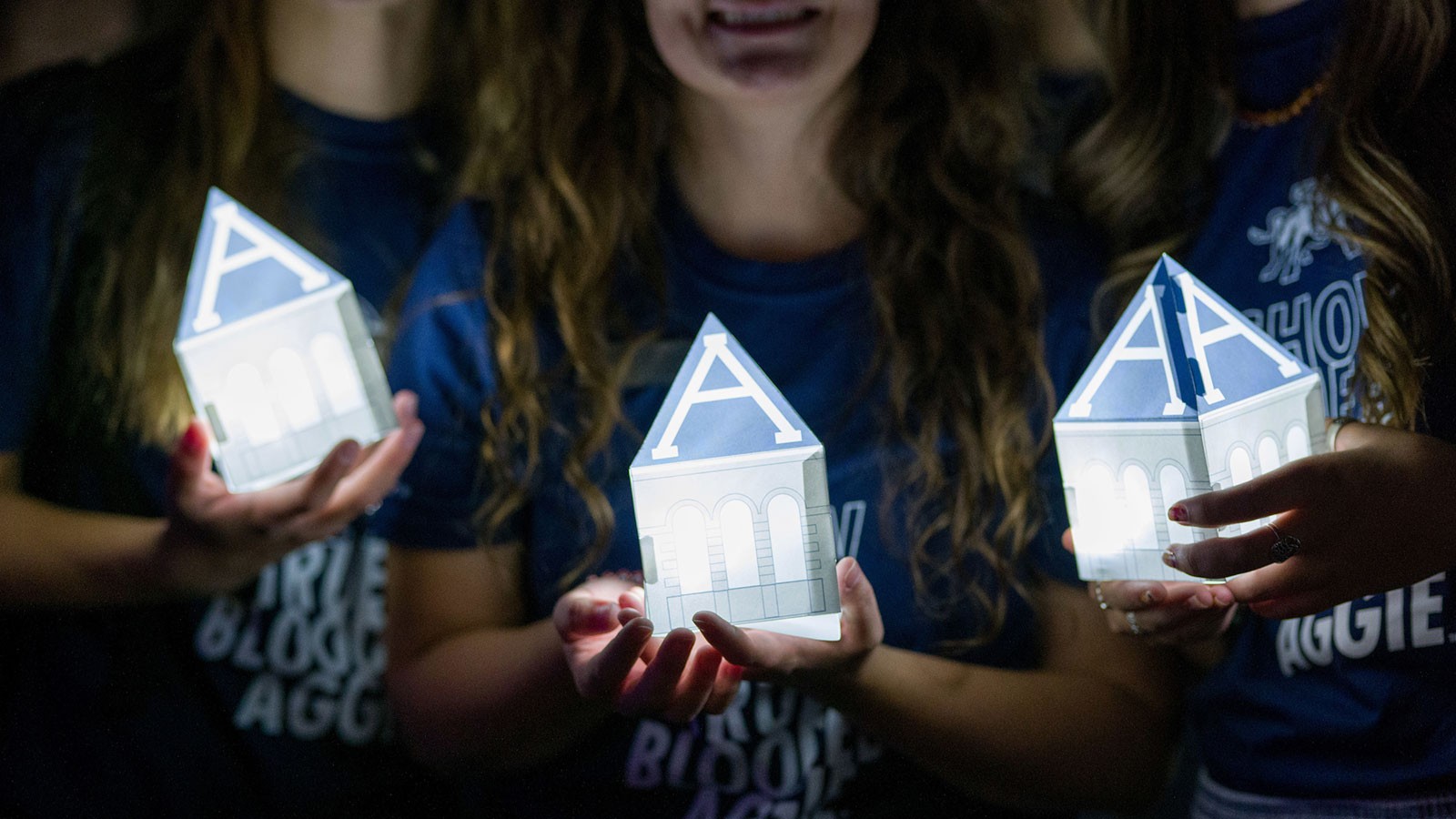 Students hold lanterns shaped like Old Main's tower.