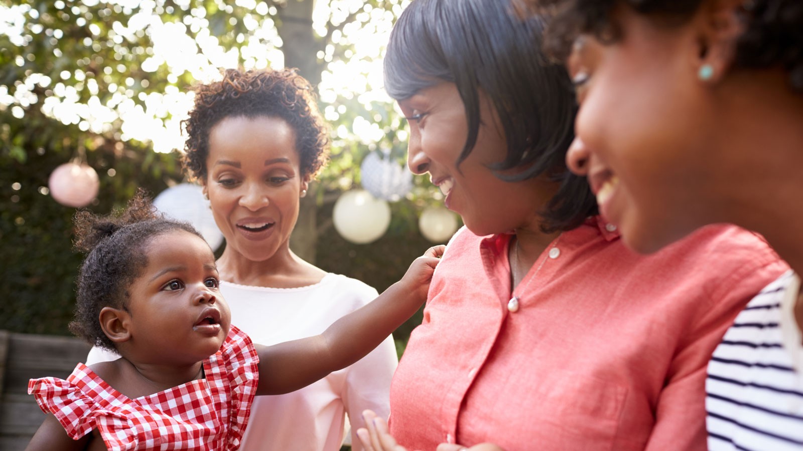 Three women look at a baby.