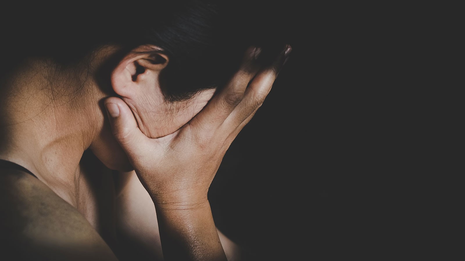 A woman holds her face in her hands.