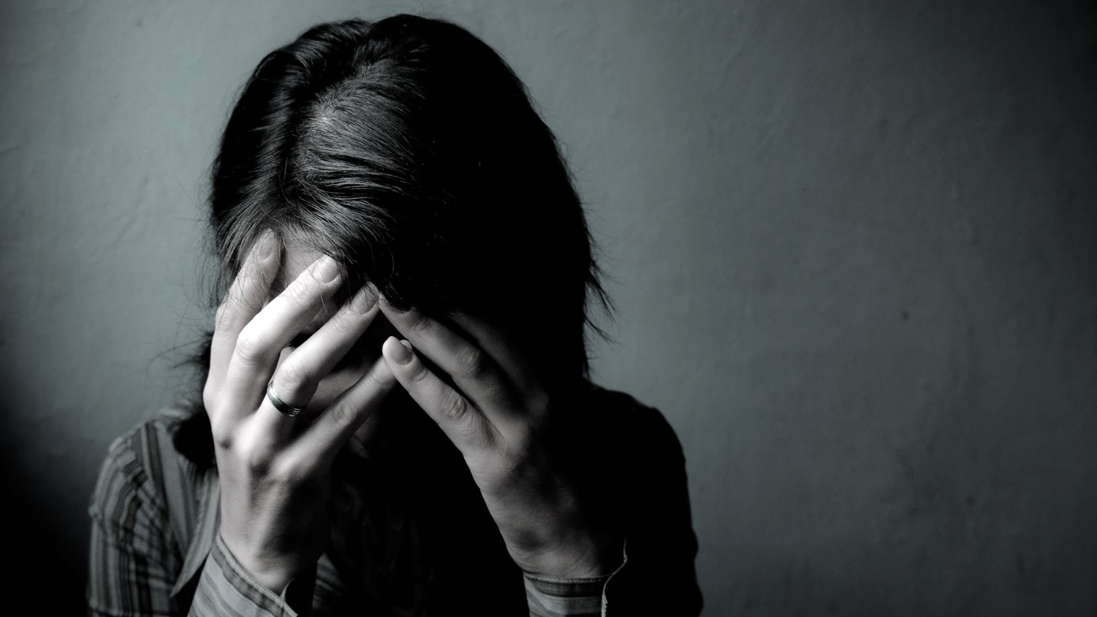 A woman holds her head in her hands in anguish.