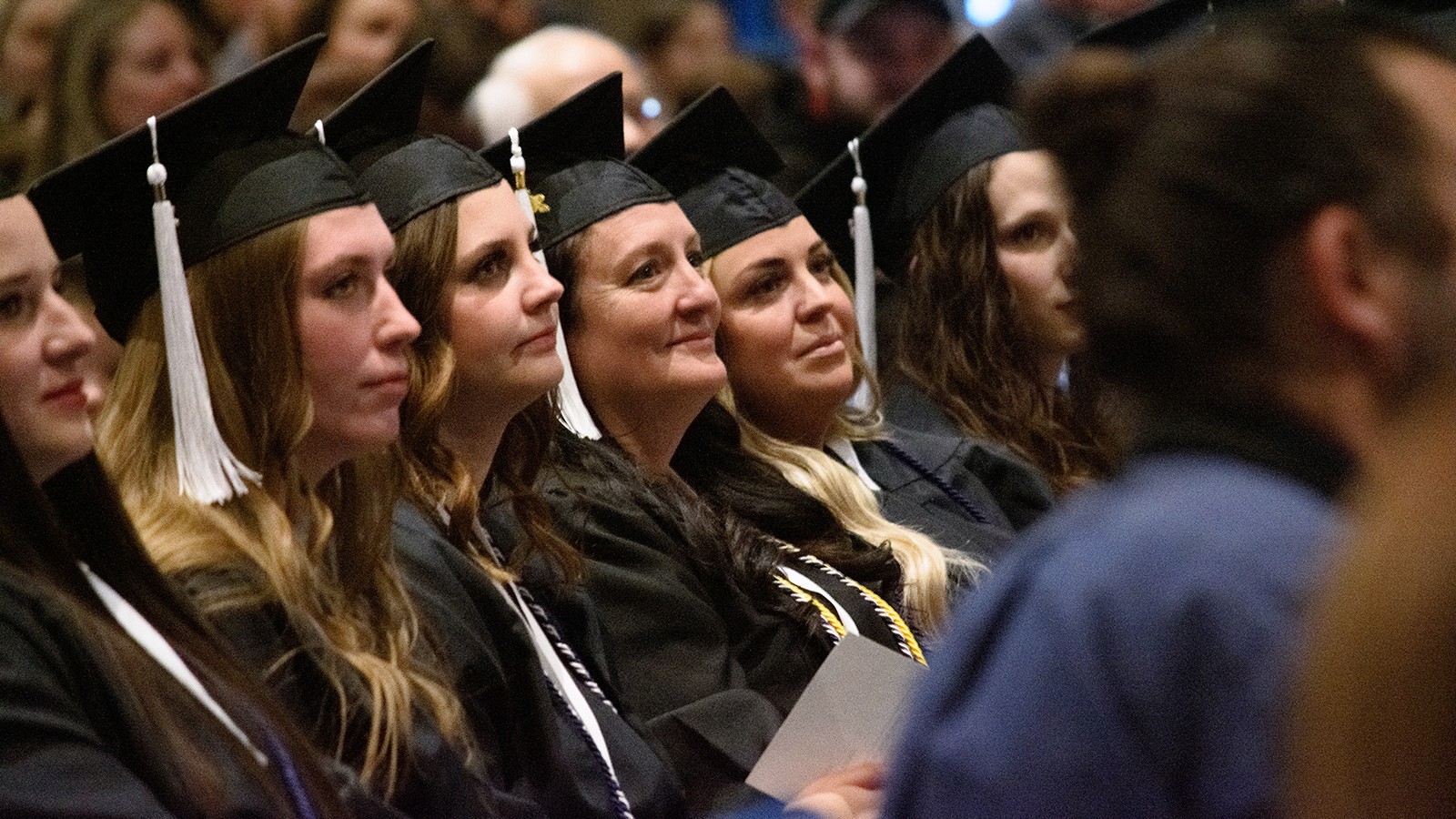 Graduates sit in chairs listening