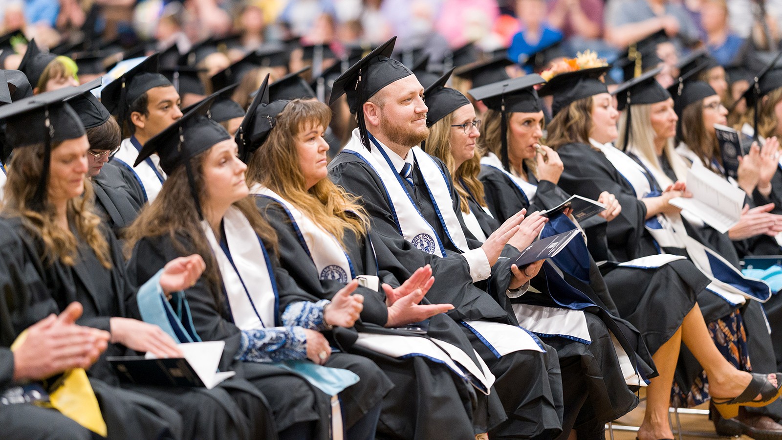 Graduates sit in chairs listening