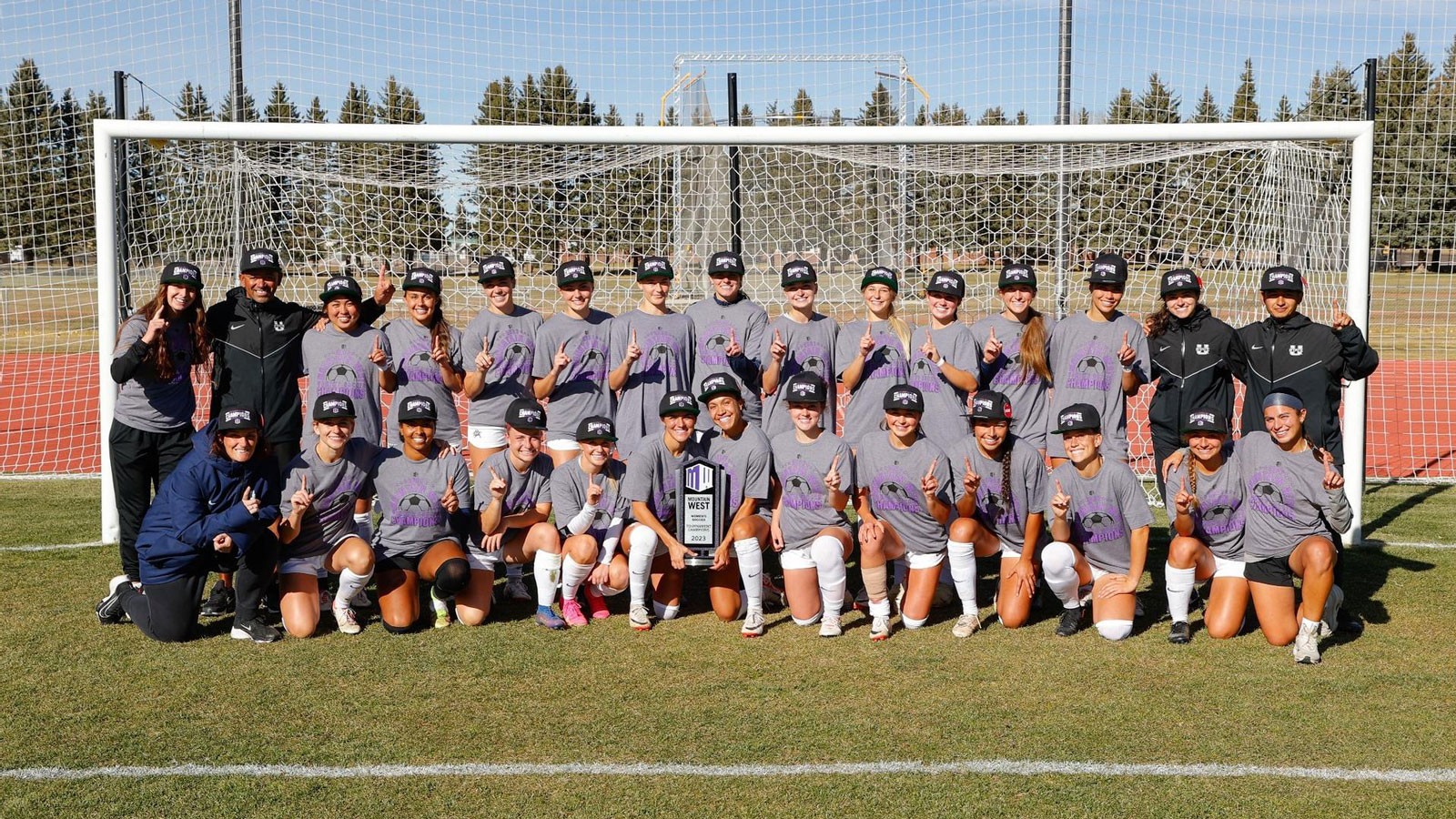 The USU Women's Soccer team posing for a photo in a goal.