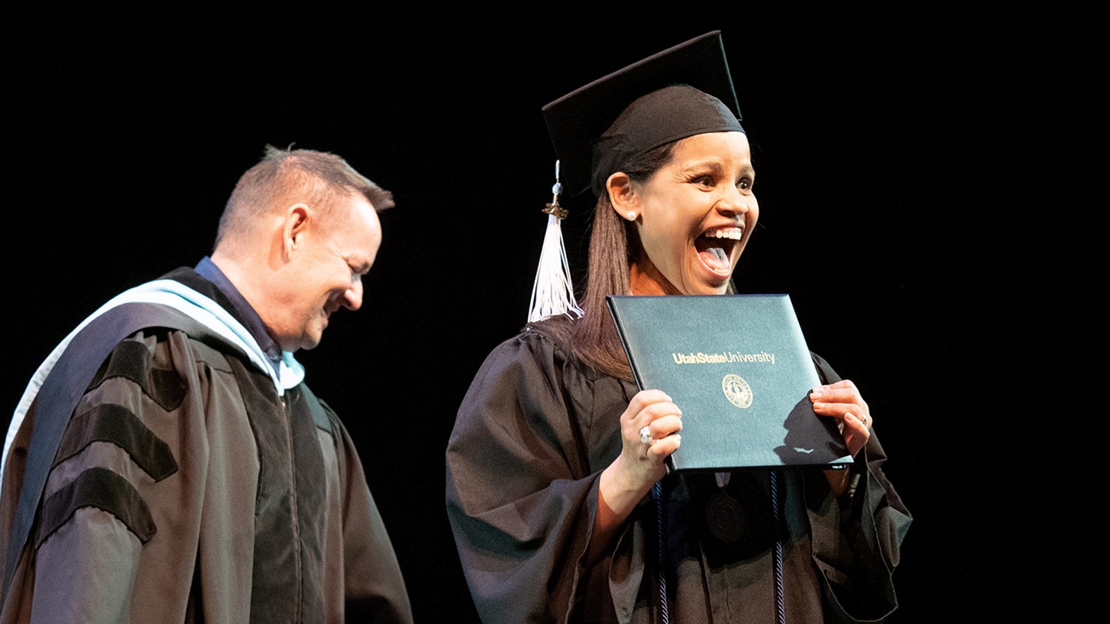Woman smiles holding diploma cover