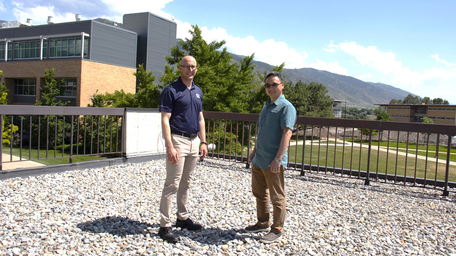 Two men stand on a rooftop.