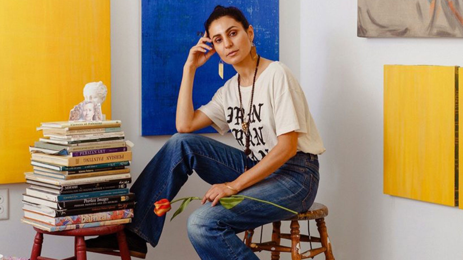 An artist sitting next to a stack of books.
