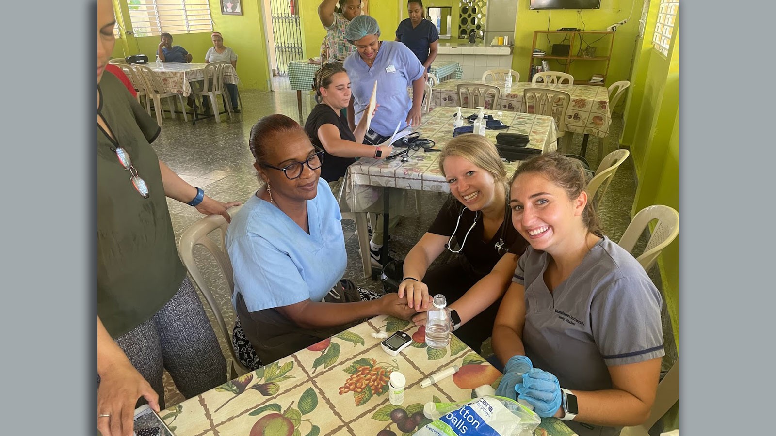 Nursing students teaching a patient to use a medical device.