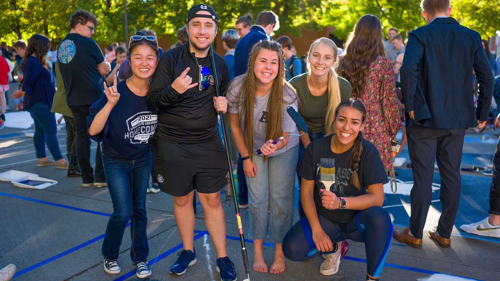 Students outdoors with painting equipment.