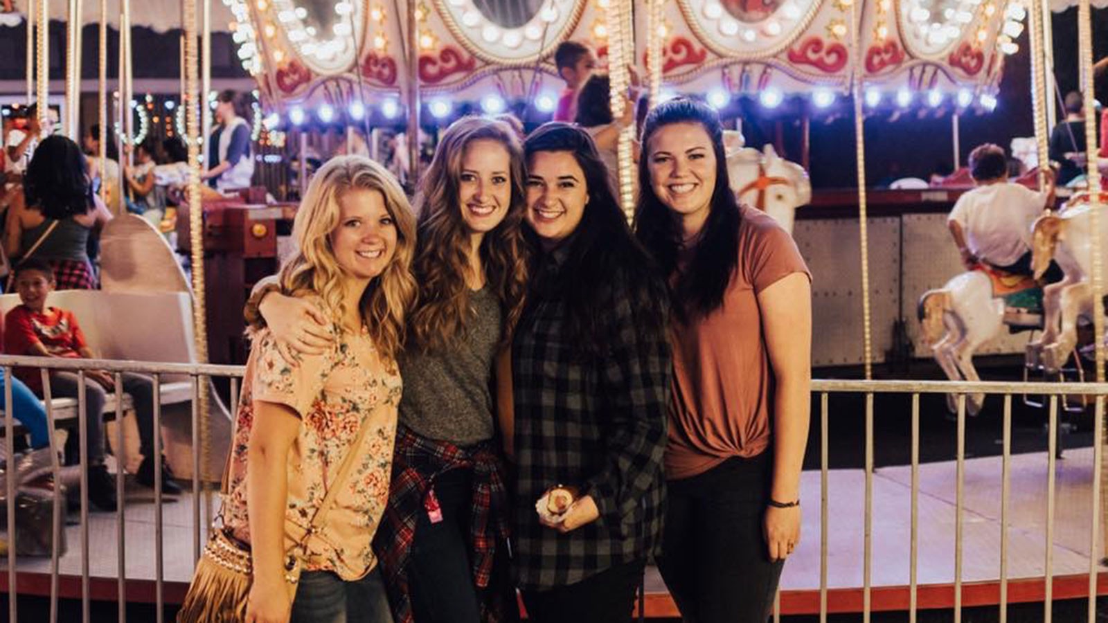 Women standing in front of a carousel.