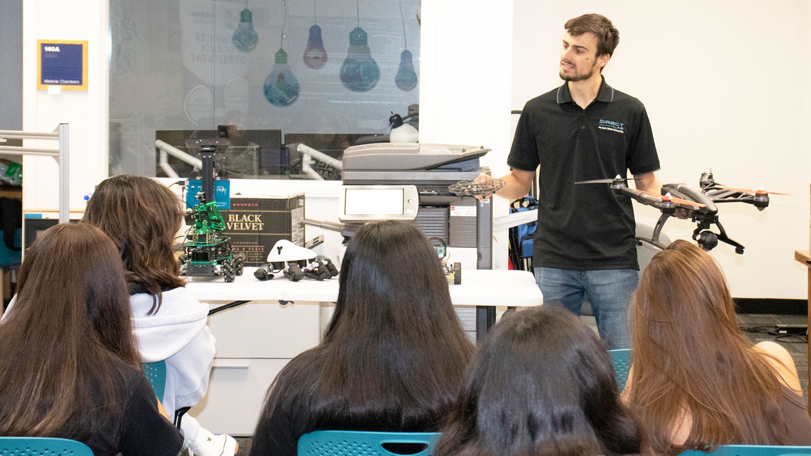 Person shows drones to group of teens.