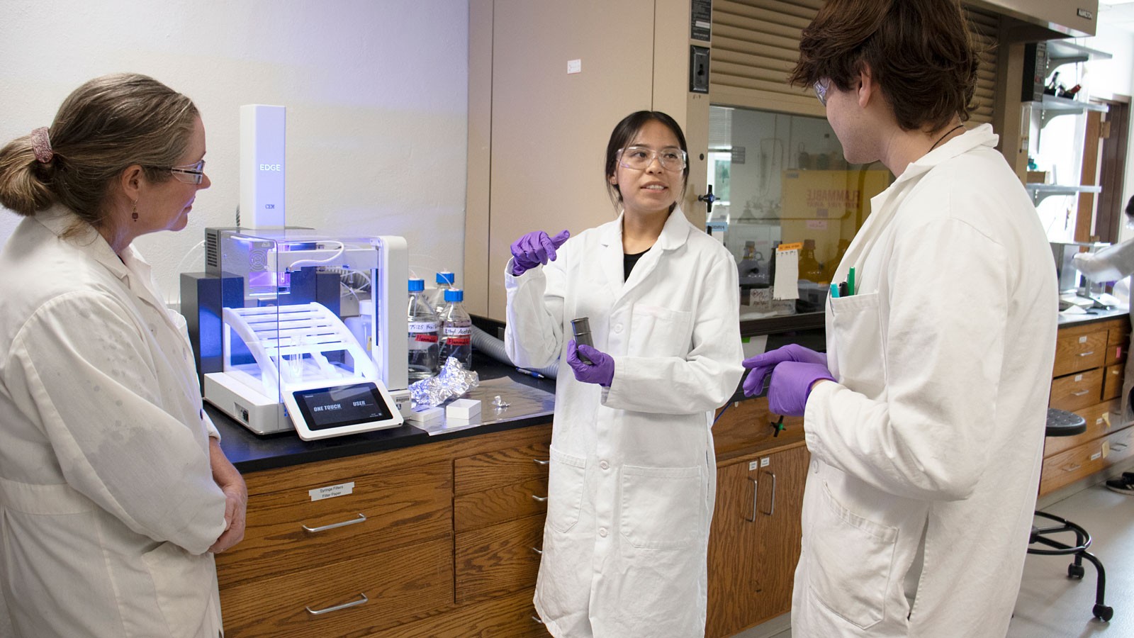 A student with mentors in the lab.