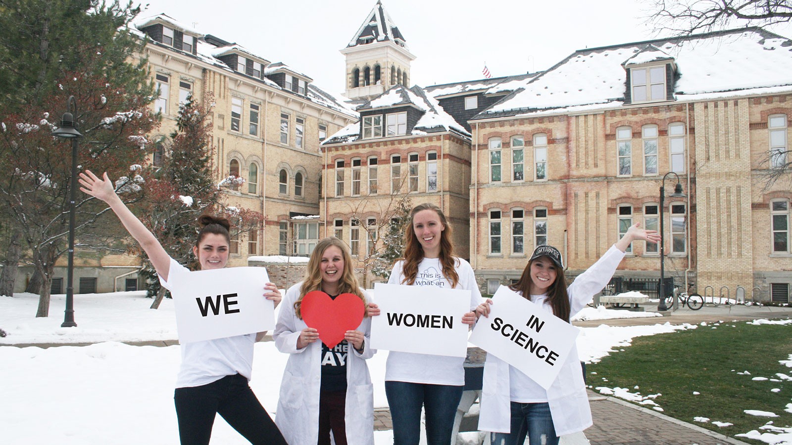 Women scientists holding placards reading "We love women in science."