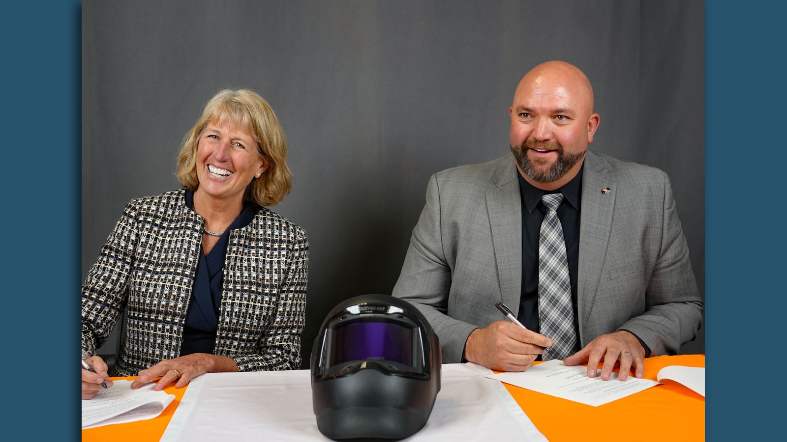 Noelle E. Cockett and Aaron Weights signing papers.