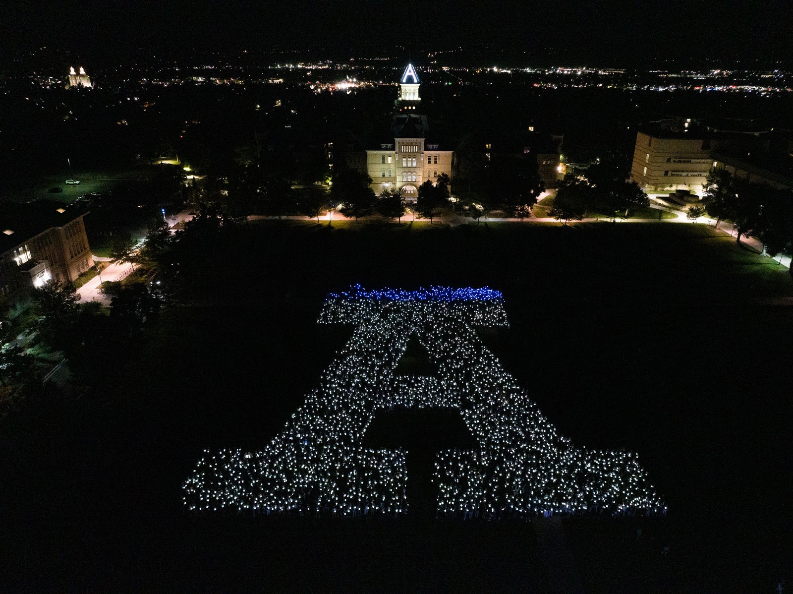 People holding lights form a giant A on the USU Quad as seen from above.
