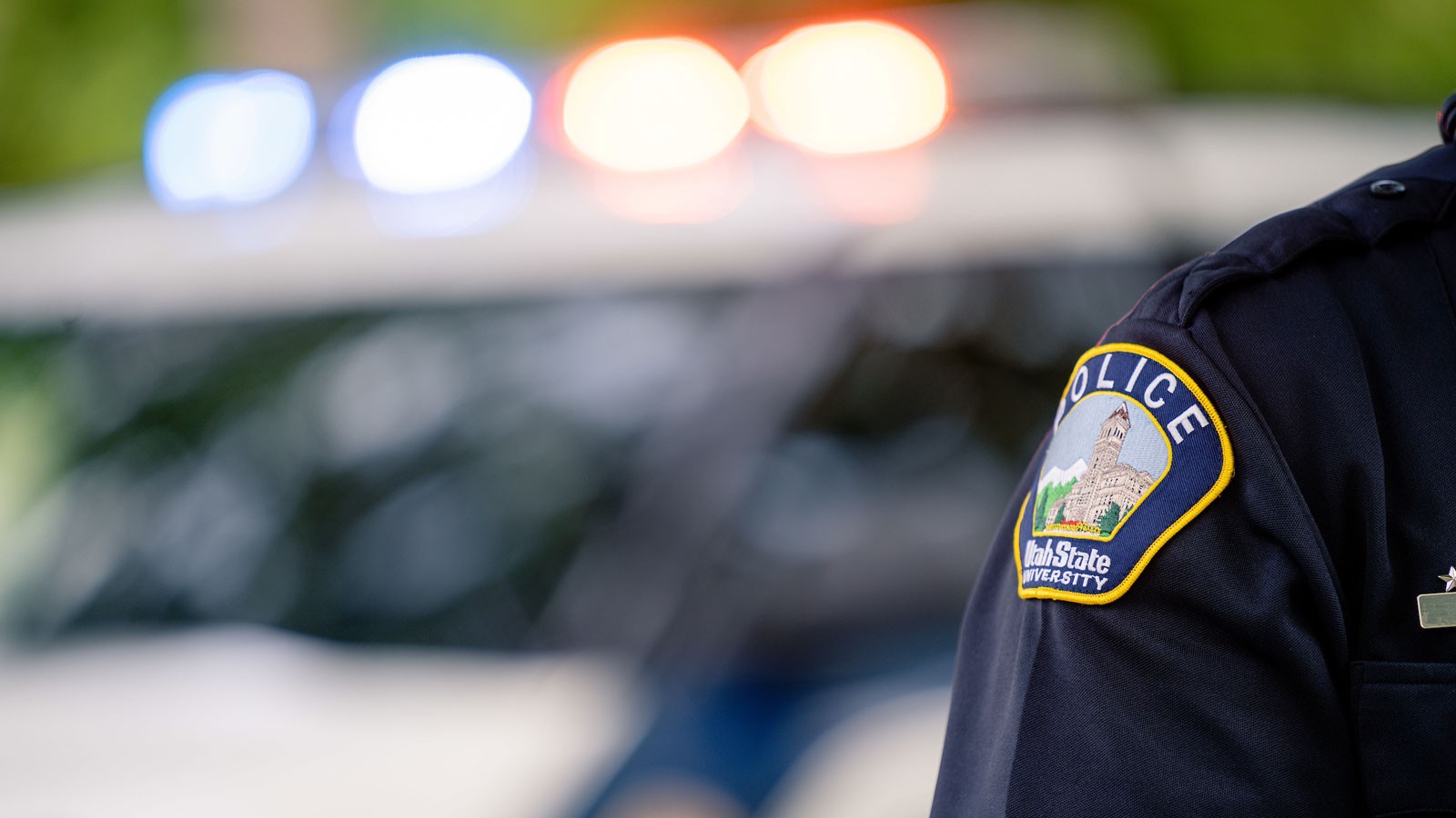 A police officer stands in front of a police car.