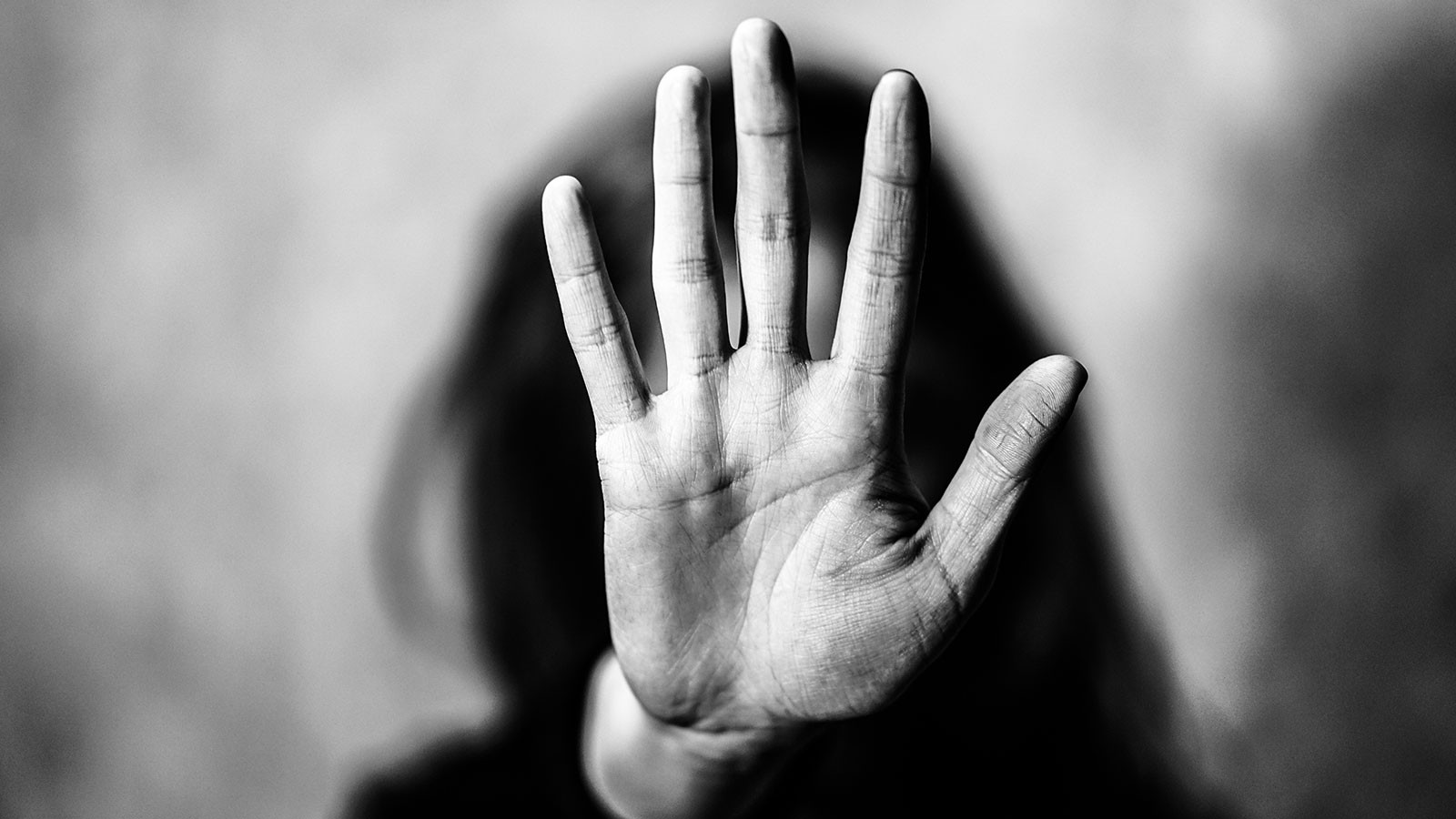 A woman holding a hand in front of her face.