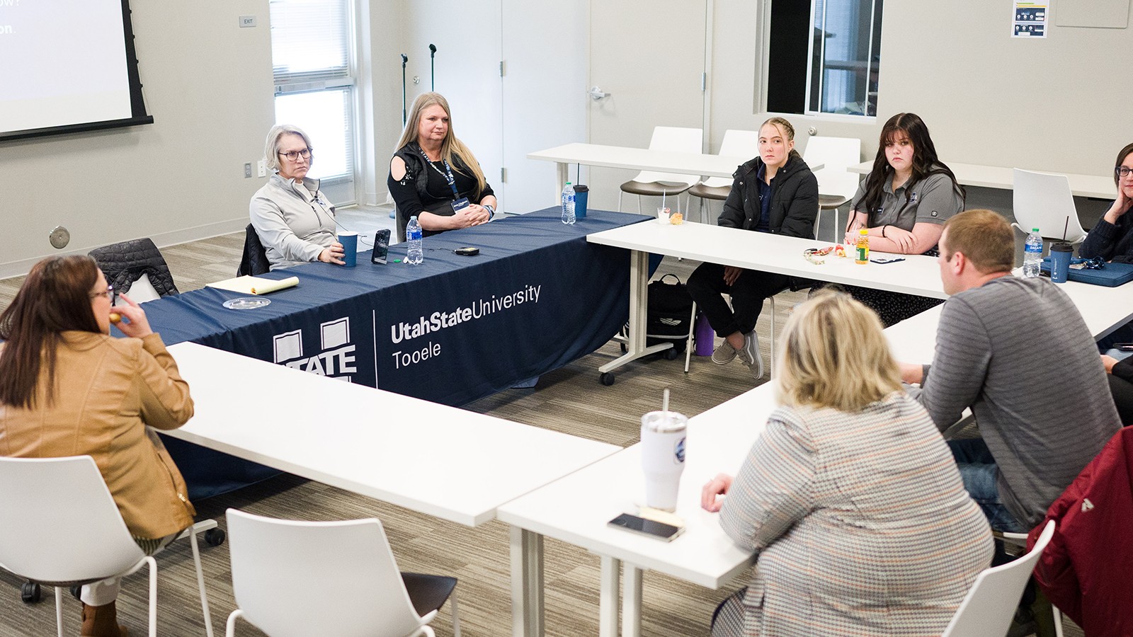 A group of people sit at a table in a discussion.