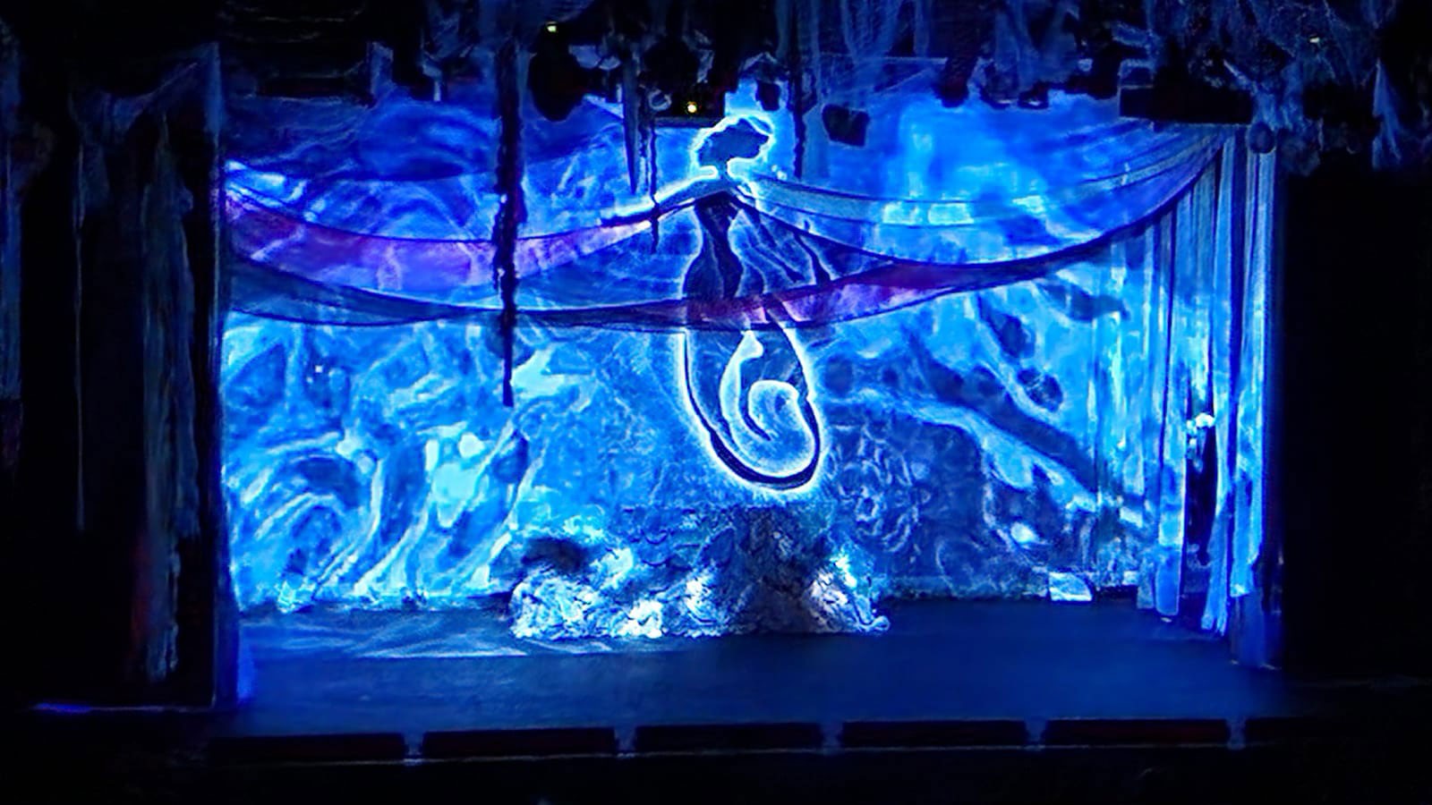 A mermaid puppet on a theater stage.