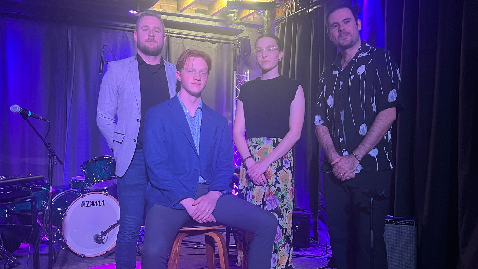 Musicians pose on stage for a photograph.