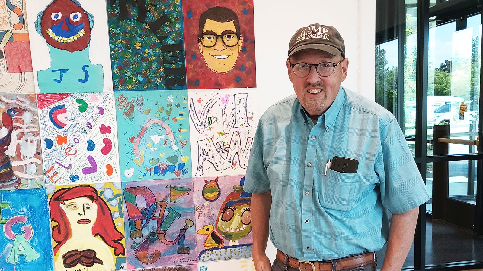 Michael Bingham stands next to an art collage.