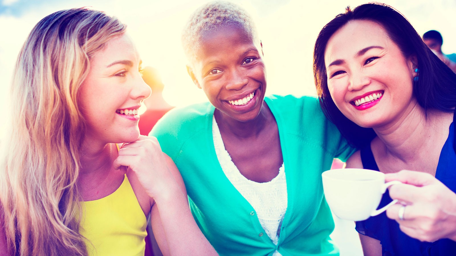 Three women smiling and embracing.
