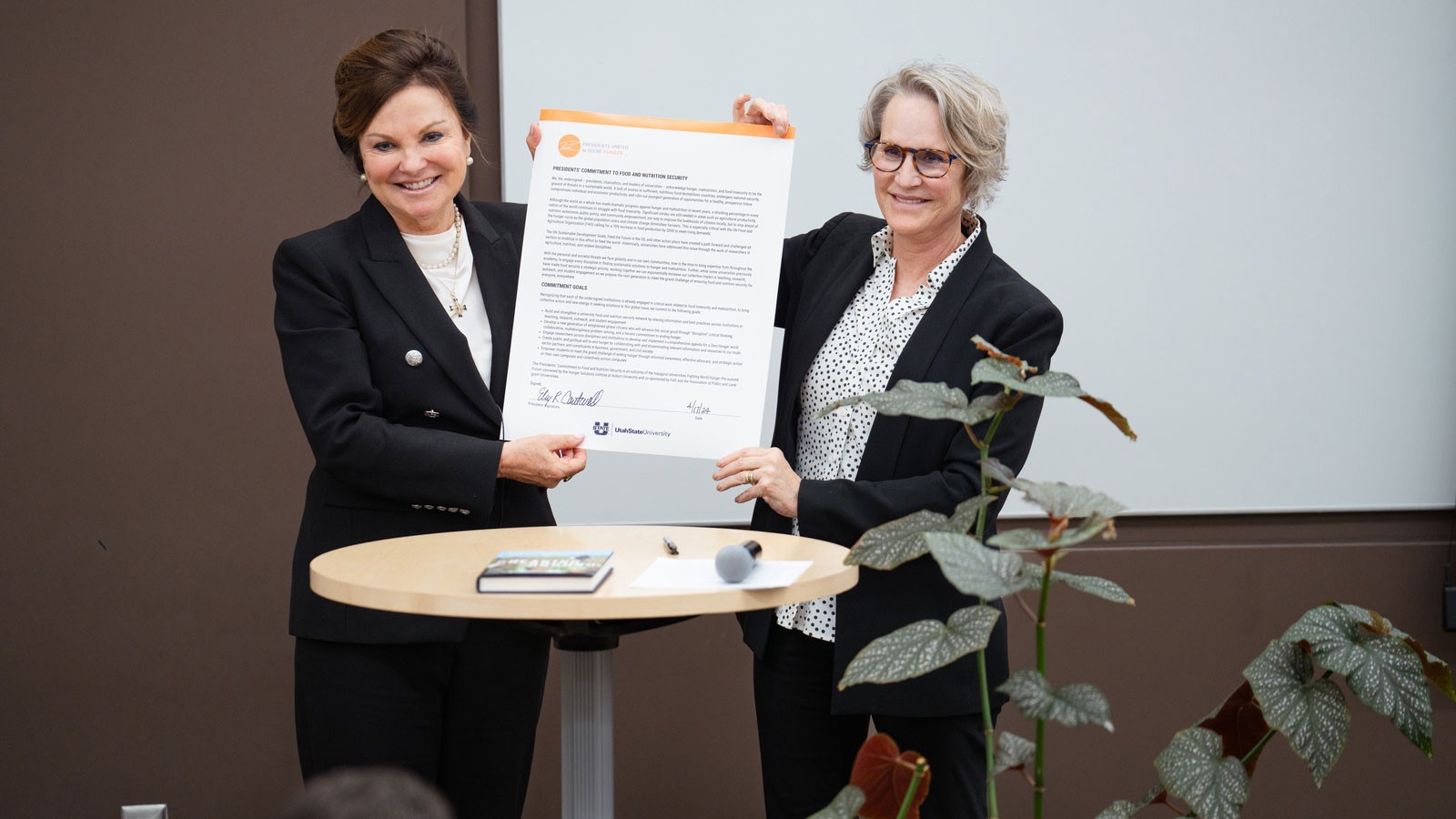 Two people holding an oversized document.