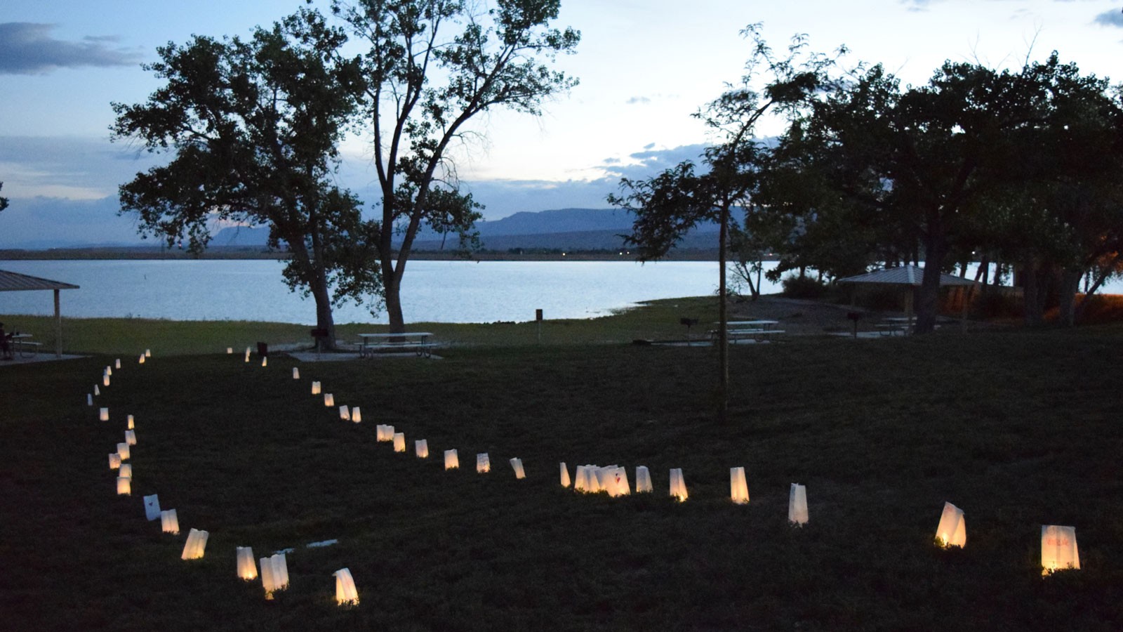Lights lining a path in a park by a reservoir.