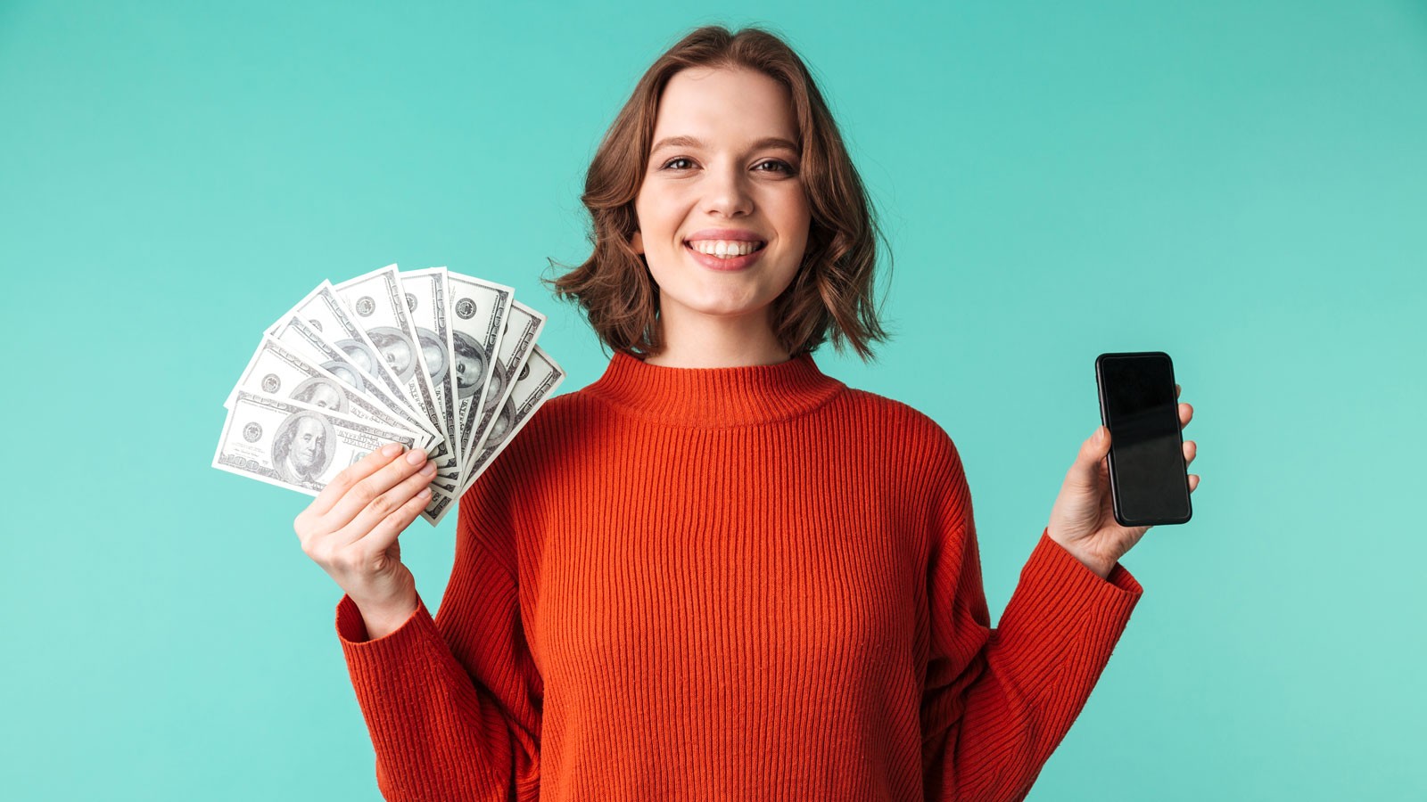 A person holding cash in one hand and a cell phone in the other.
