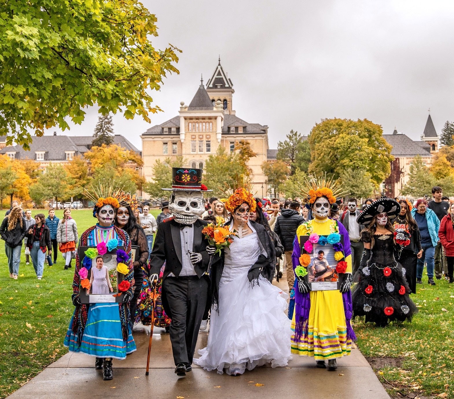 People in costume for Dia de Los Muertos walk across campus.