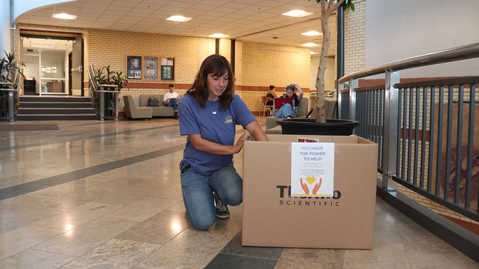 Hannah Feinsilber adjusting a cardboard box in a university building.