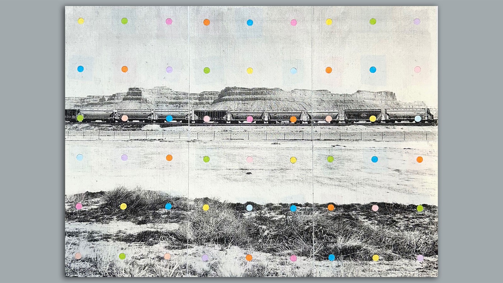 Colorful dots over a weathered photo of a train passing through the desert.
