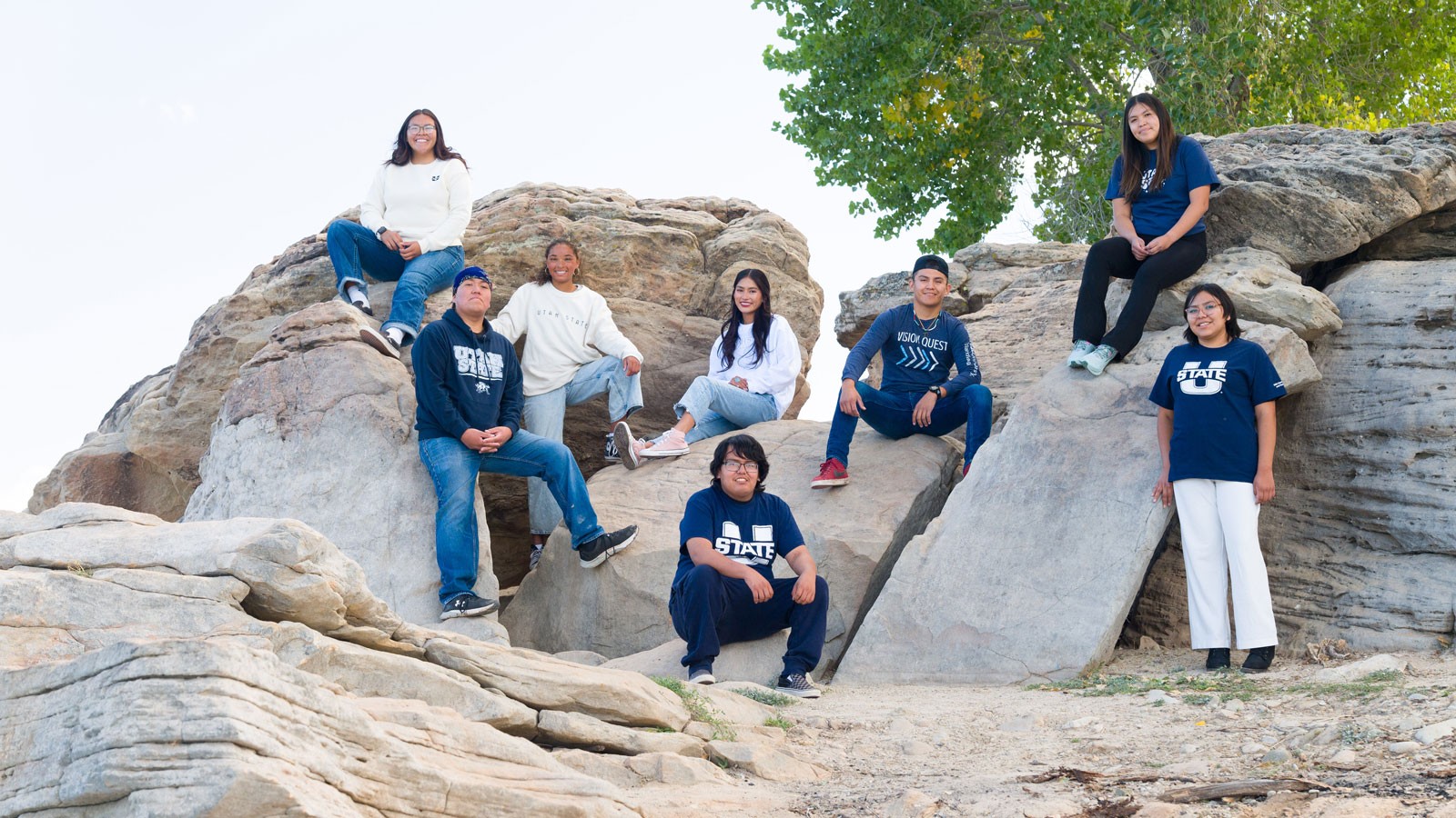 Native American students posing for a photo on a rock formation.