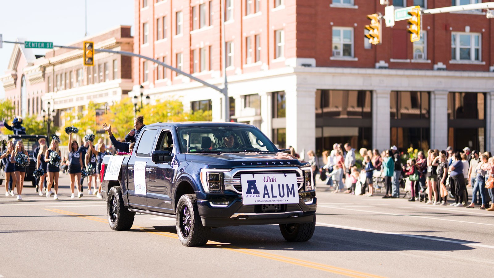 A truck with an oversize USU license plate reading "Alum" in a parade.