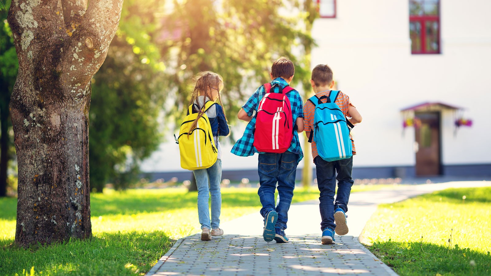 Three children walking on a sidewalk.