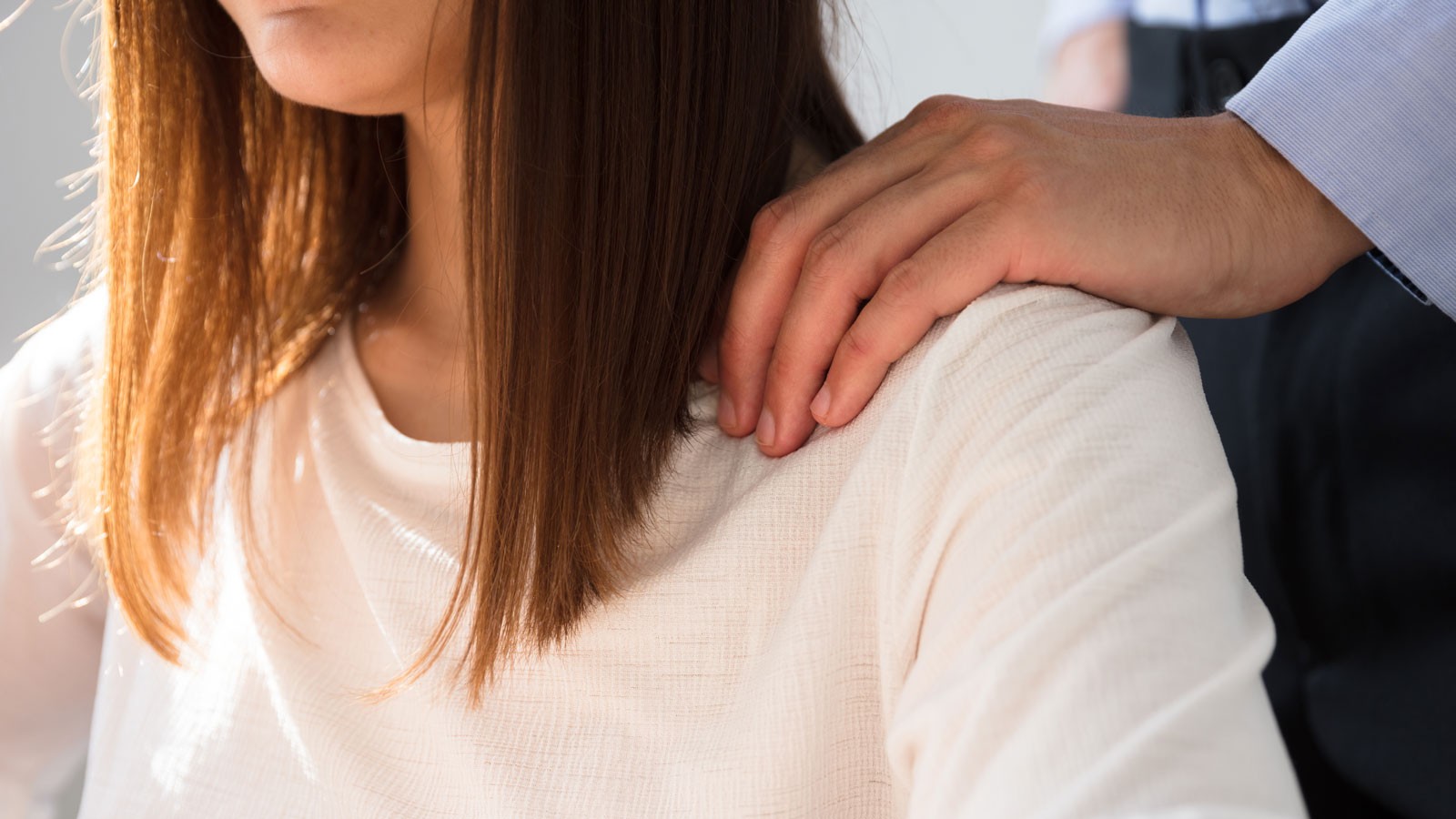 A man placing his hand on a woman's shoulder.