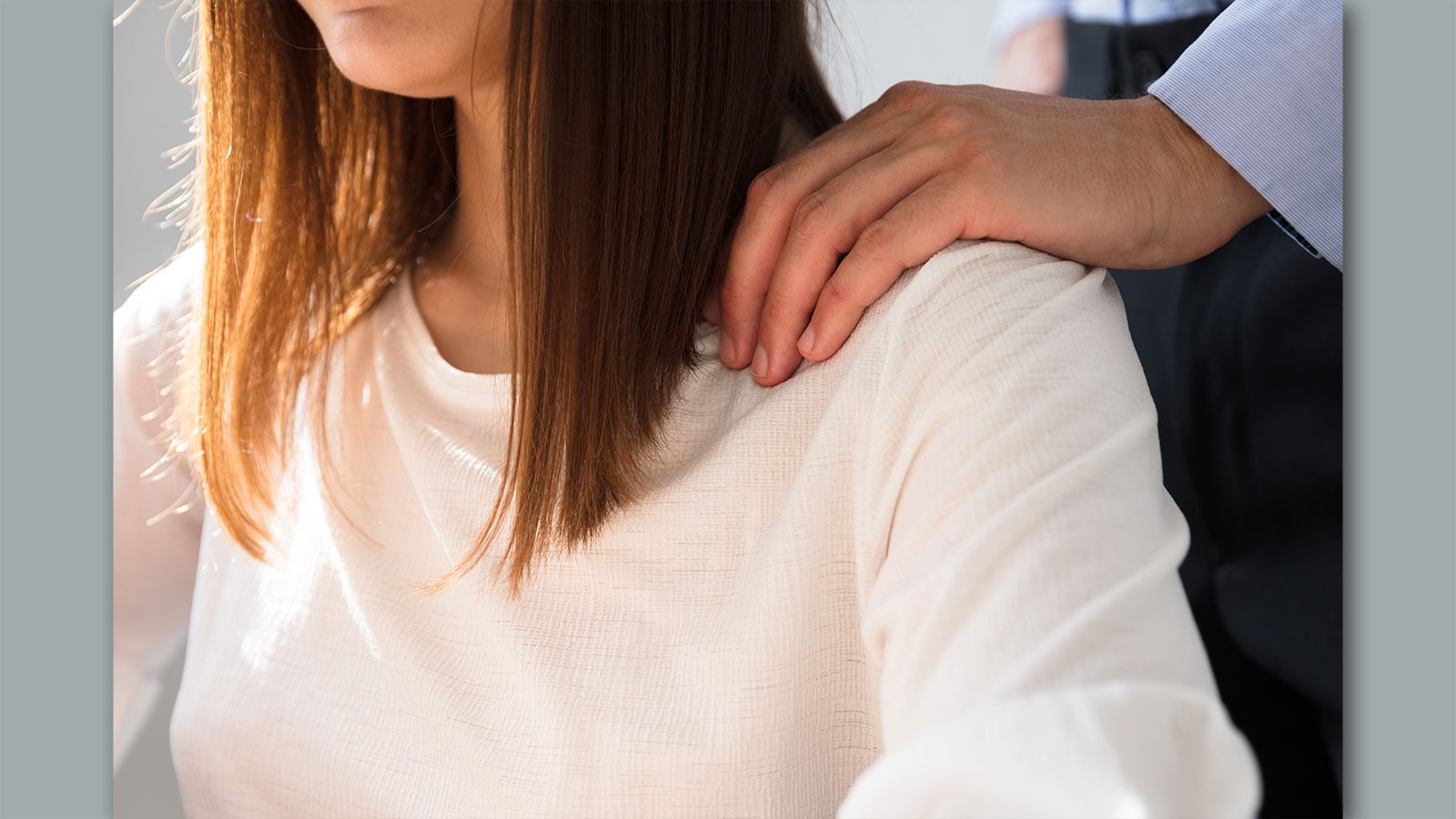 A woman with a man's hand on her shoulder.