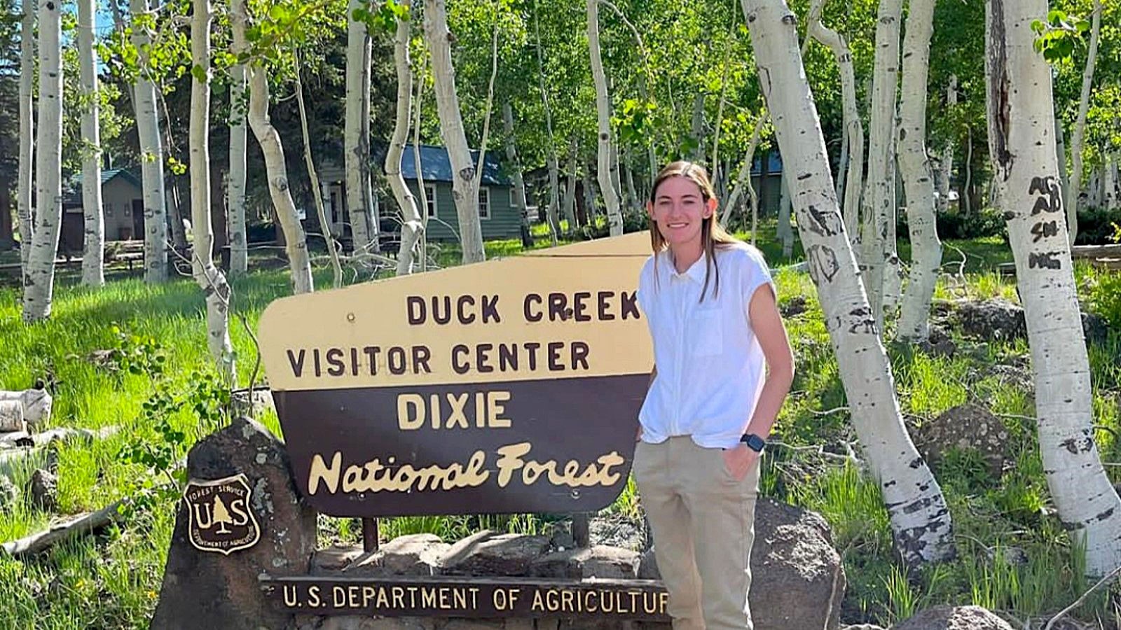 Callie Davis posing by a sign that says Duck Creek Visitor Center, Dixie National Forest.