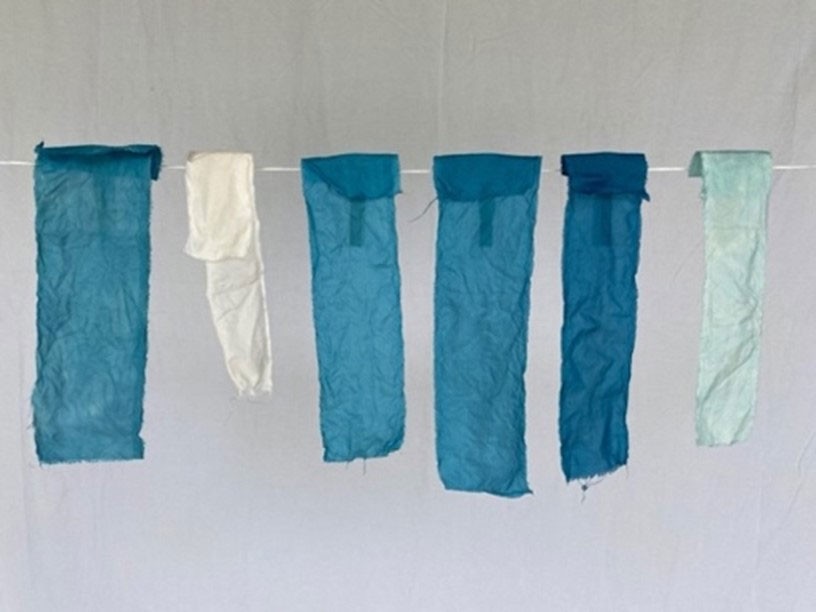 Strips of blue-dyed cloth hanging on a drying line.