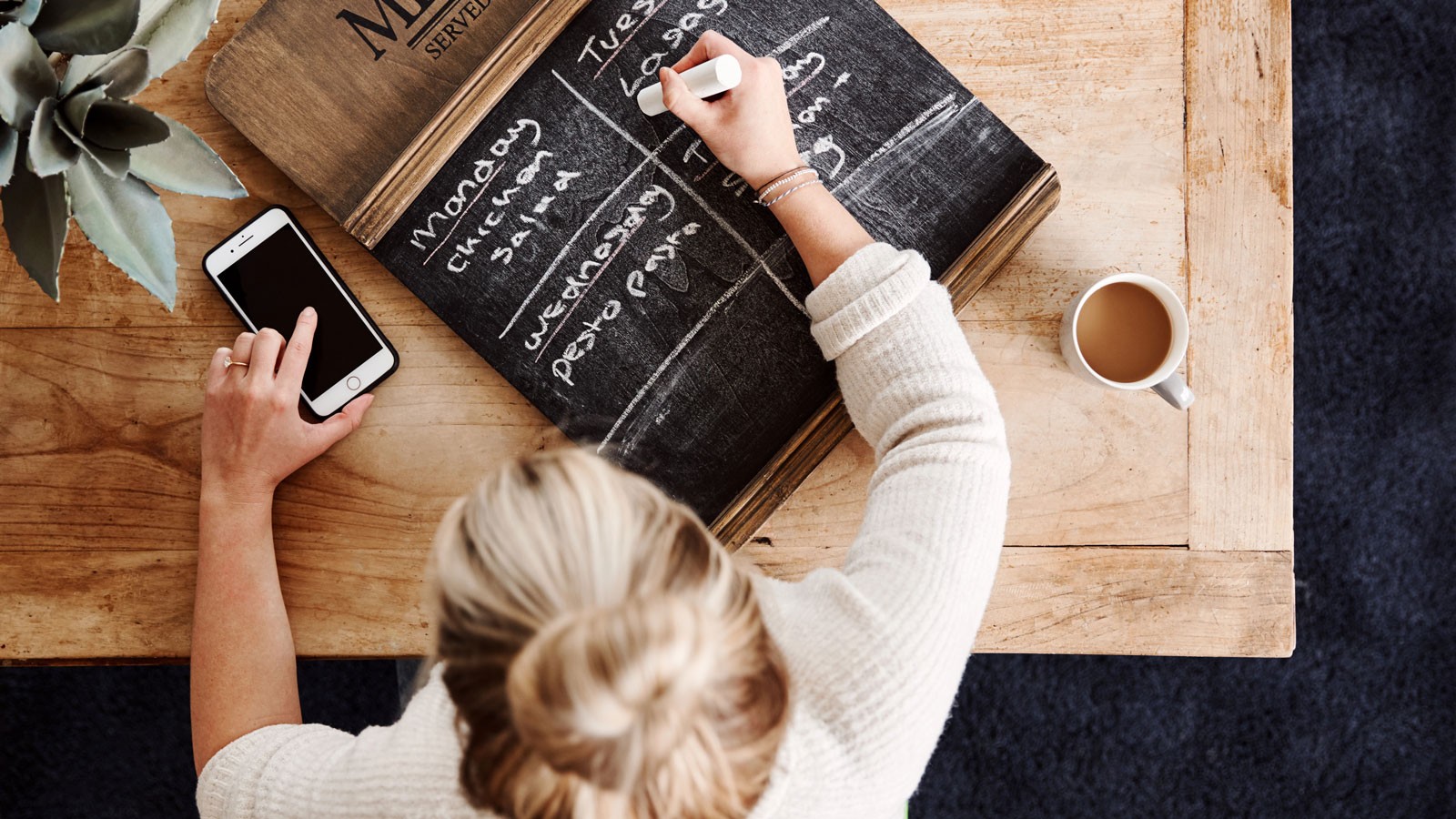 A person writing a meal plan on a chalkboard.