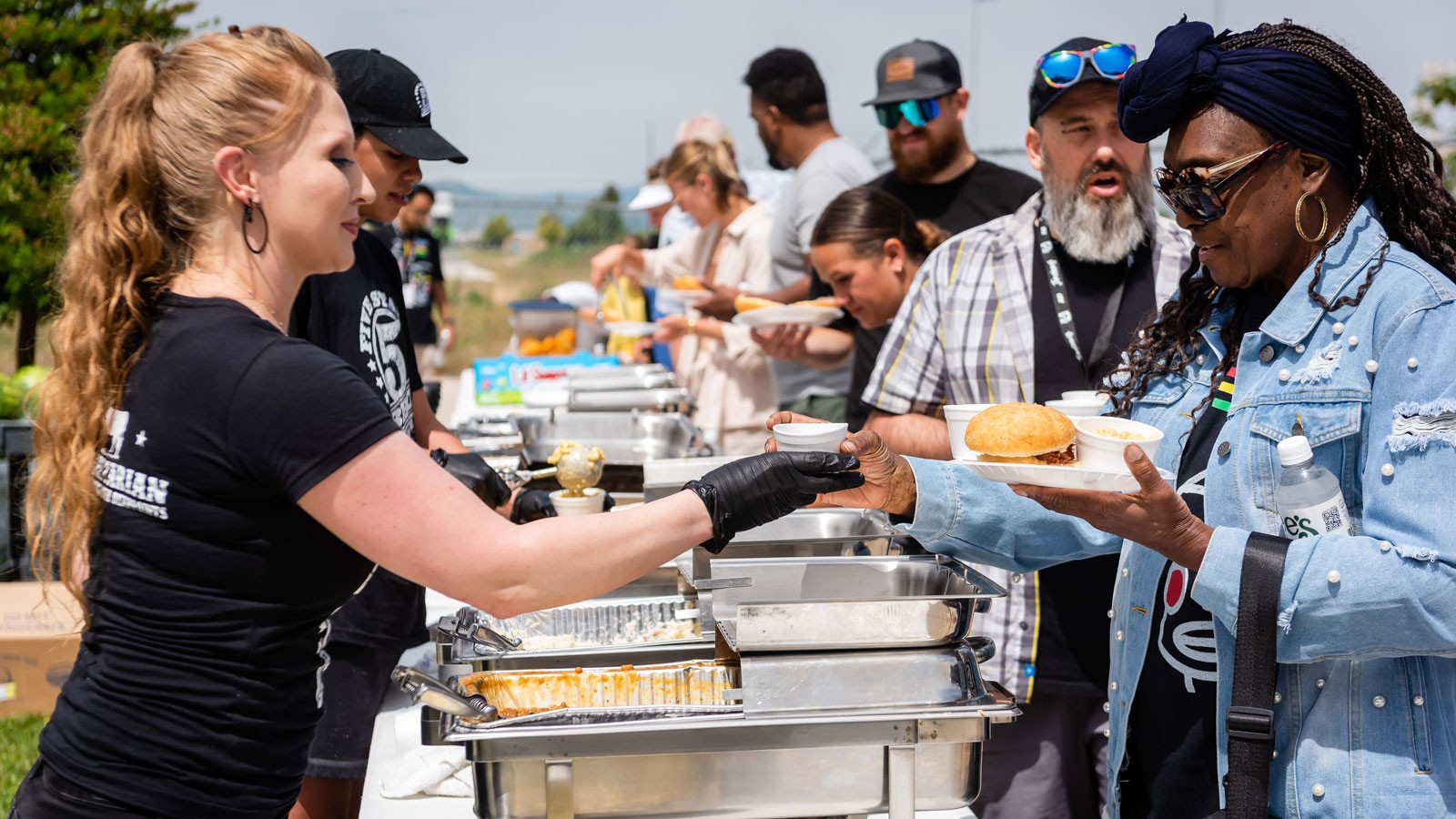 People getting food at a barbecue dinner.