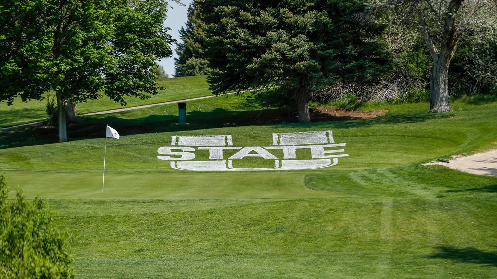 U State logo near a putting green on a golf course.