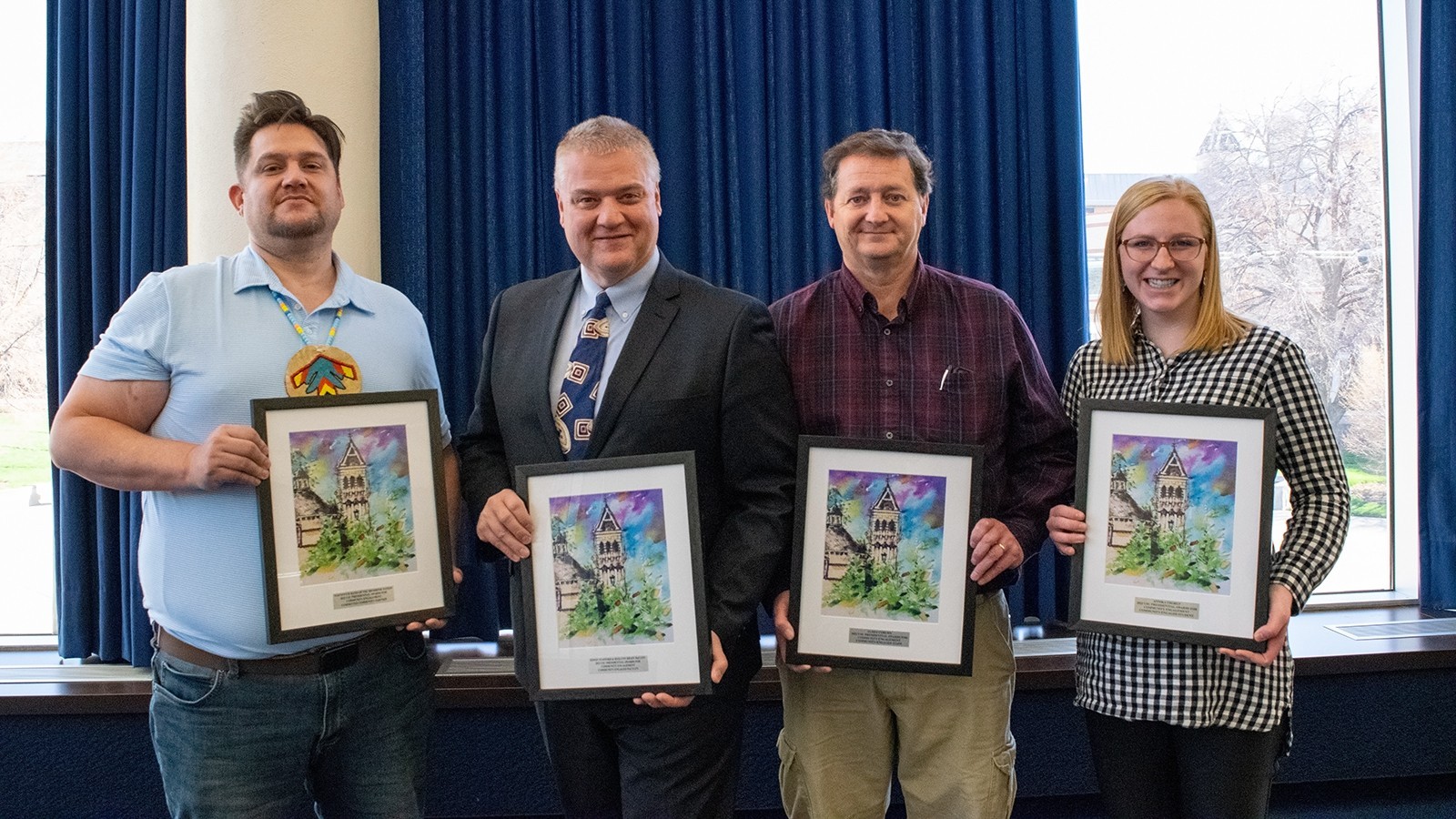 Four people hold a framed award