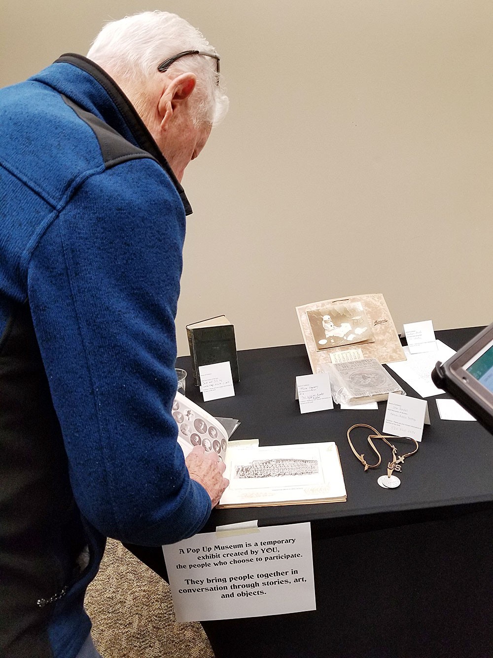 An elderly man examines objects at a "We Will Remember Them" World War One roadshow.