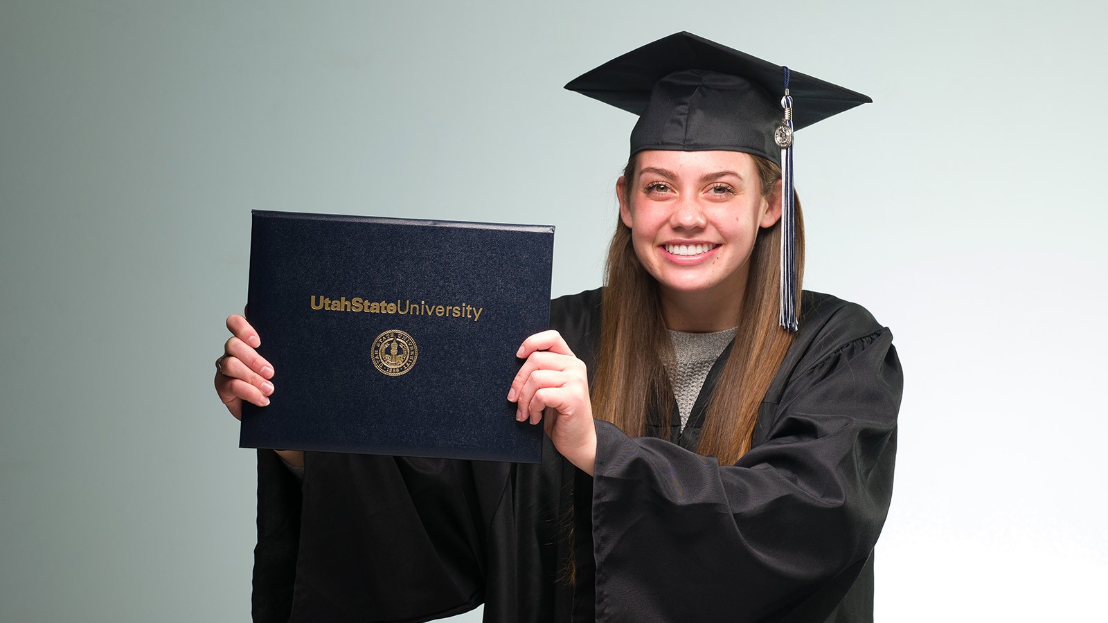 USU graduate holding their diploma cover.