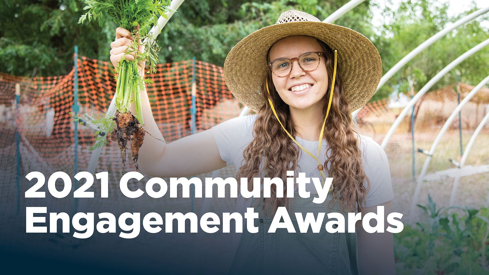 USU student holding a bundle of freshly-picked carrots.