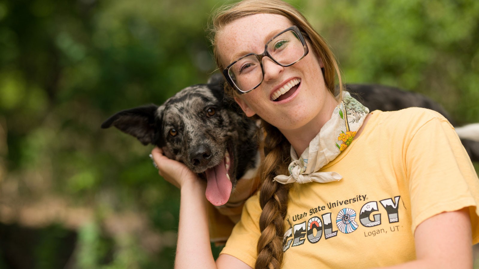 A Utah State University Student poses with a dog.