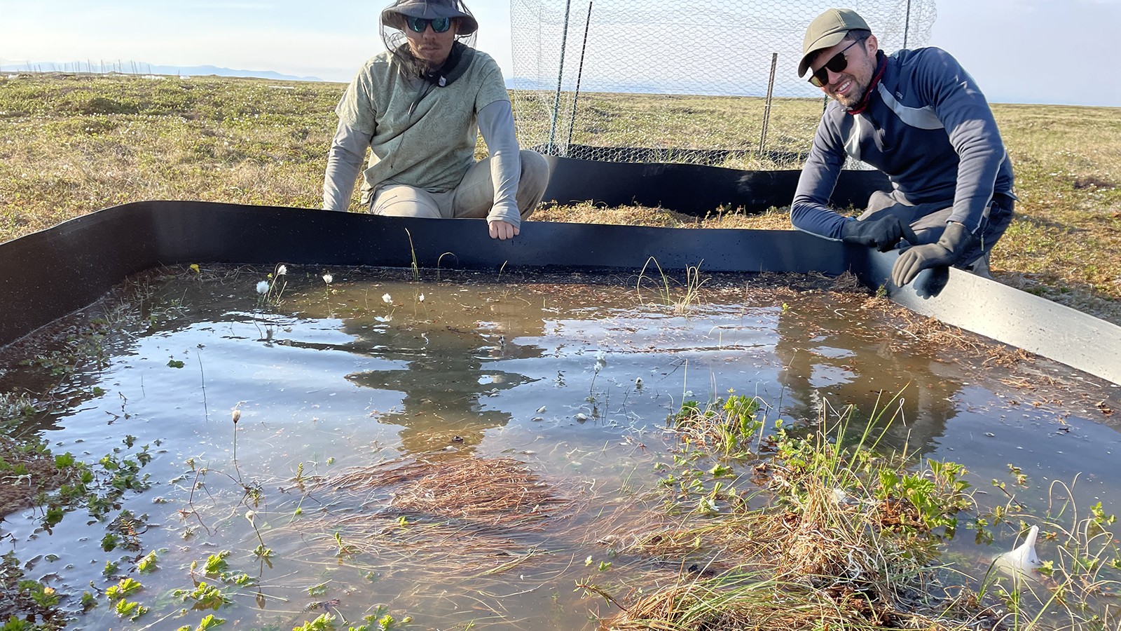 Two students work on a enclosed piece of land covered in salt water