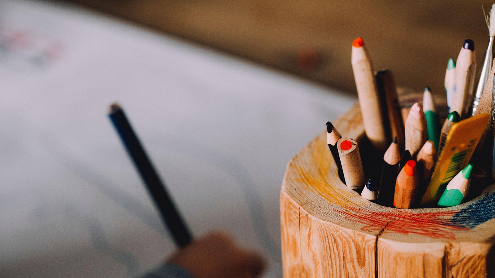 colored pencils in wooden jar on a desk.