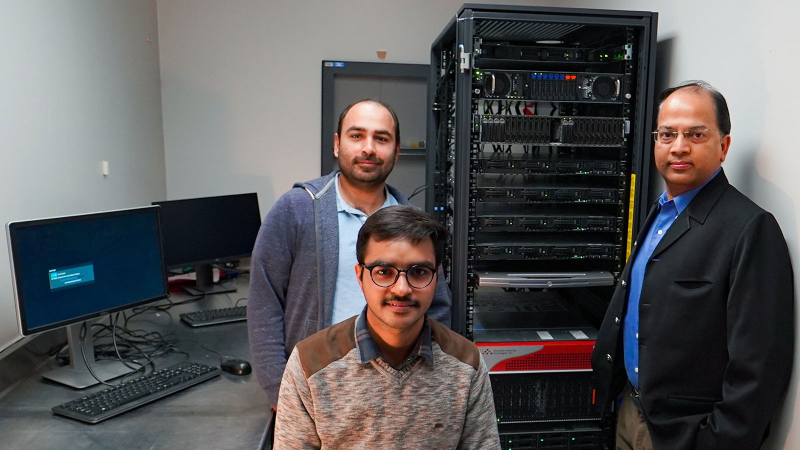 Researchers Naveen Duhan, Kartik Saini and Rakesh Kaundal pose in front of a computer server.