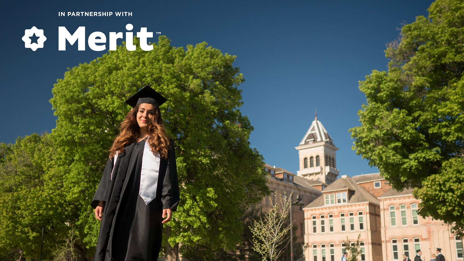 USU graduate with Old Main in the background.